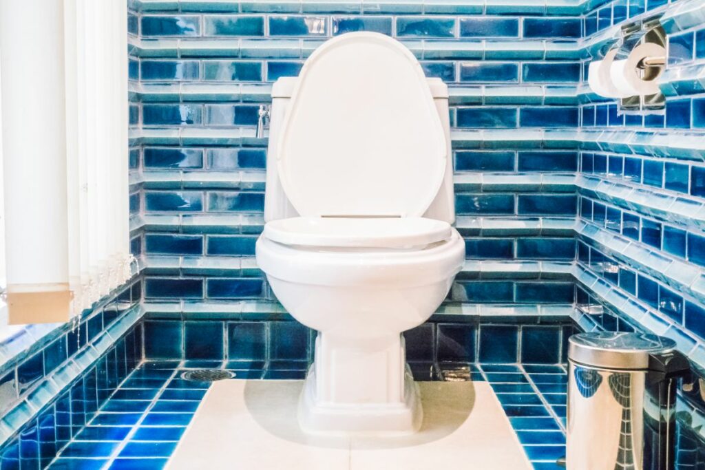 White toilet in a room with blue tile walls. 
