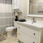 Beige bathroom with cream vanity and white toilet.