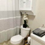 White toilet with an orchid on top and stripe shower curtain.