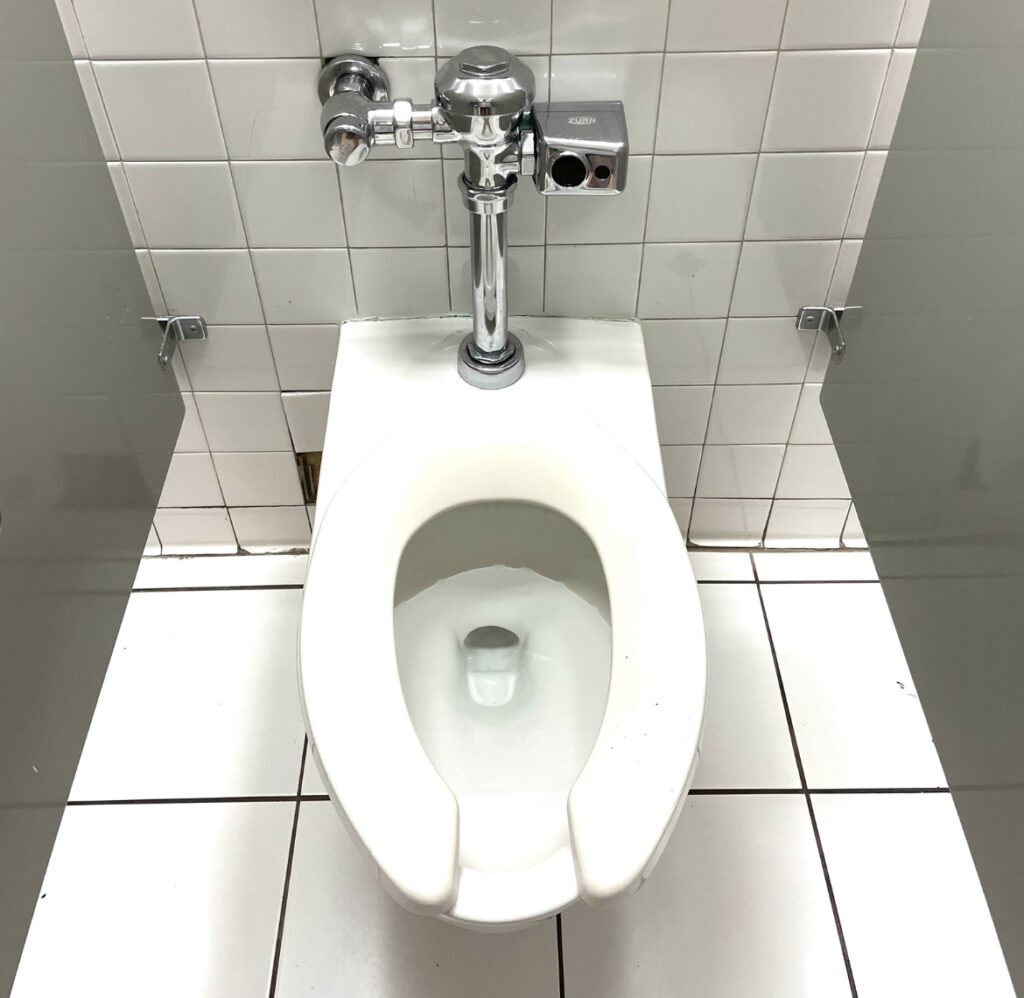 White toilet in bathroom with white tile. 