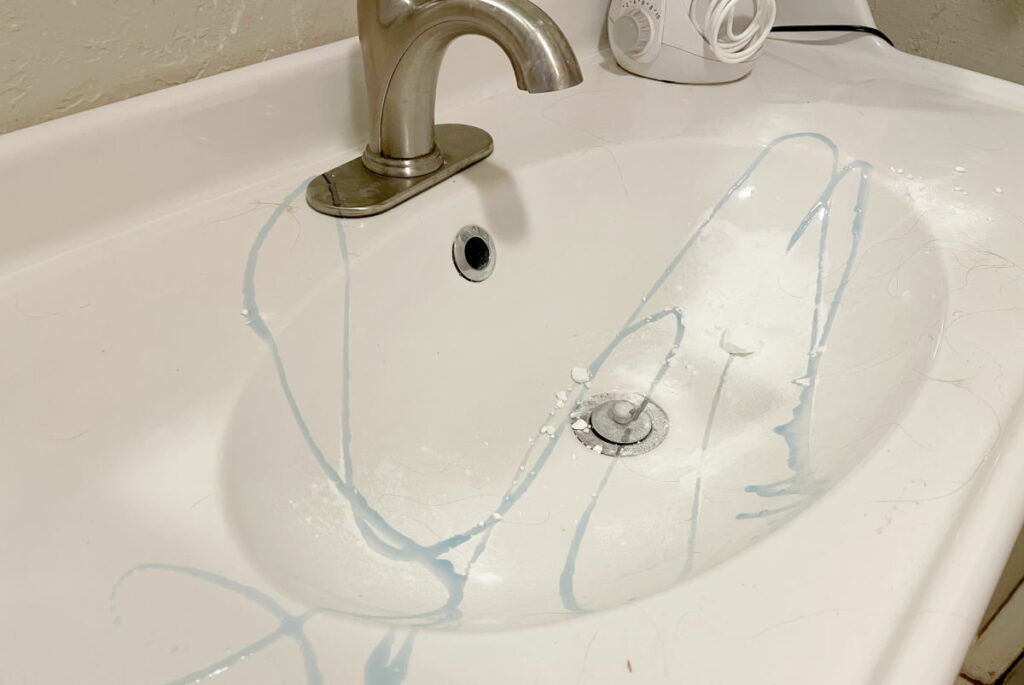 Dish soap and baking soda poured into the basin of a white sink. 