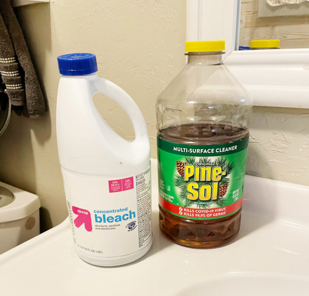 Bleach and Pine Sol bottles sitting on a bathroom counter top. 