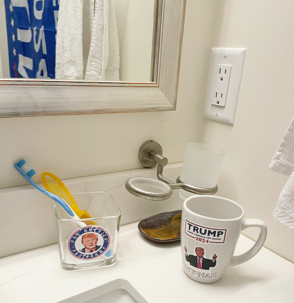Bathroom accessories with Donald trump decals on them on a white counter. 
