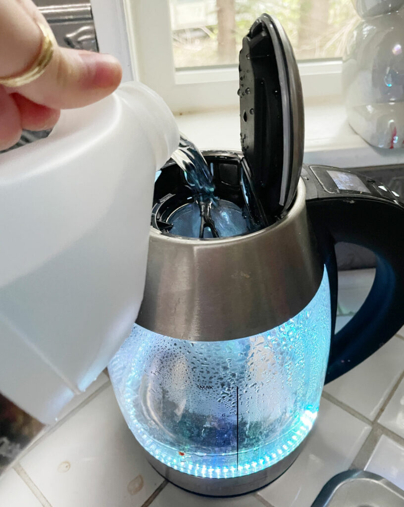 Boiling vinegar in a kettle to clean mildew from a shower drain. 